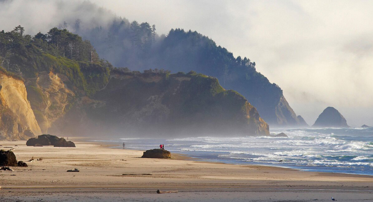Ocean, bluffs, sand and clouds in sky.