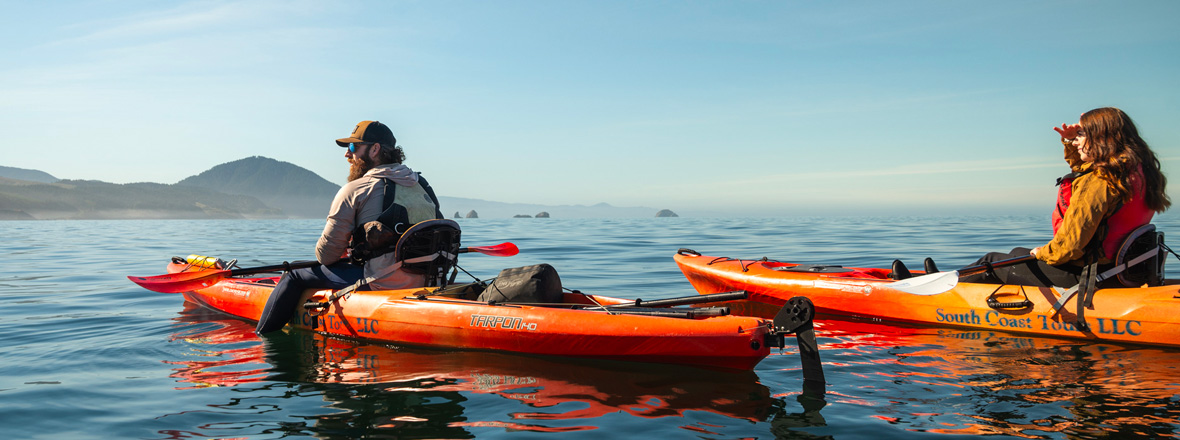 A man and woman in kayaks on an open body of water.