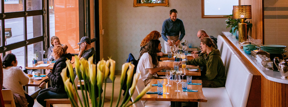 Several tables of people enjoying a meal inside a restaurant.