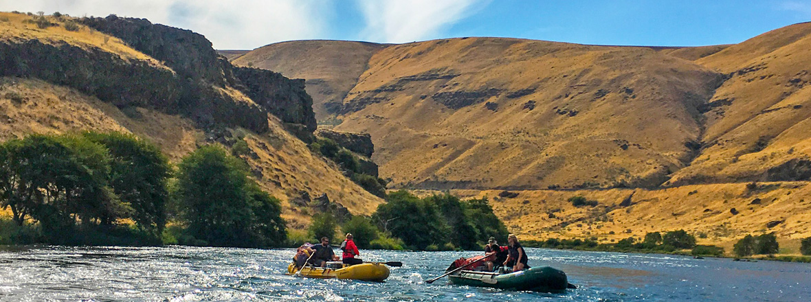 Two rafts float down a river canyon.