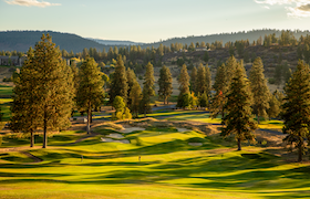 Scenic golf course framed by pine trees and rolling hills in Central Oregon.
