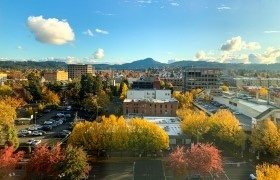 Downtown Eugene framed by vibrant fall foliage and a clear view of Spencer Butte.