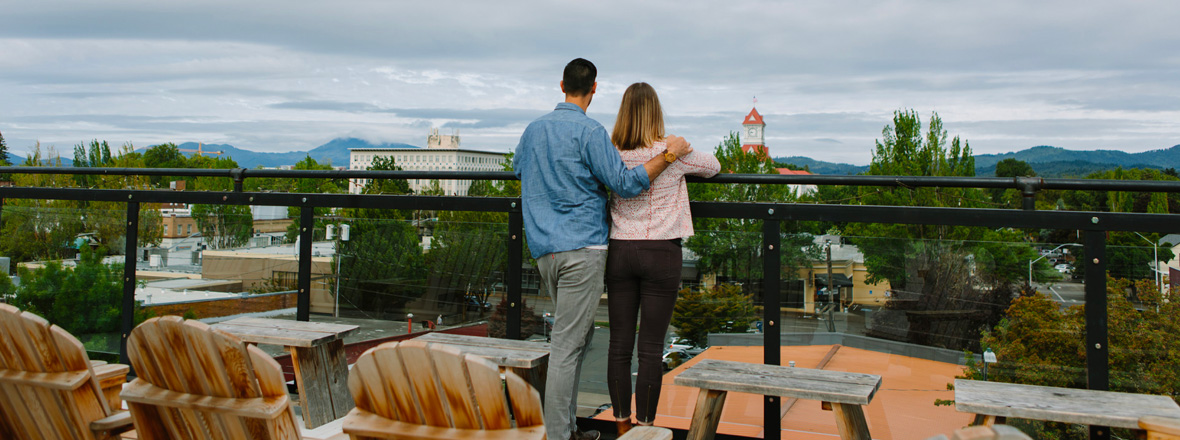 A couple looking at a city view from a rooftop patio.