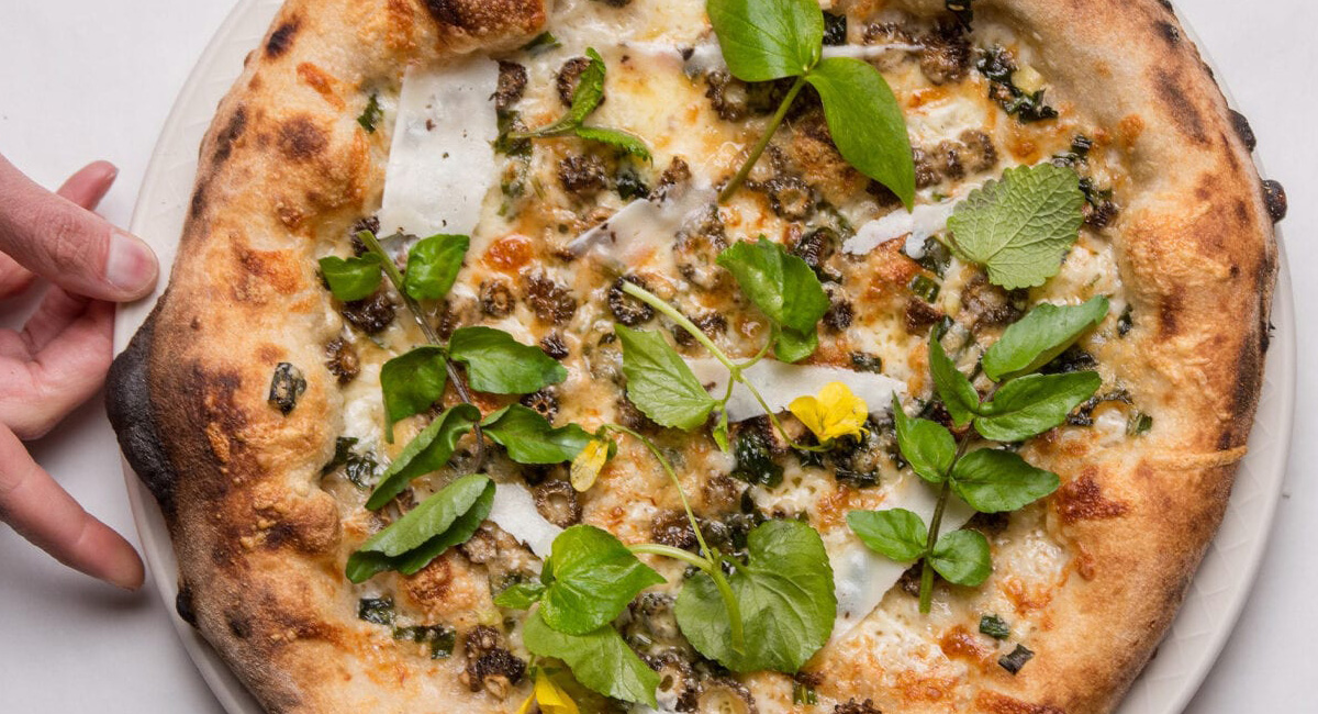 Pizza topped with cheese and fresh greens.