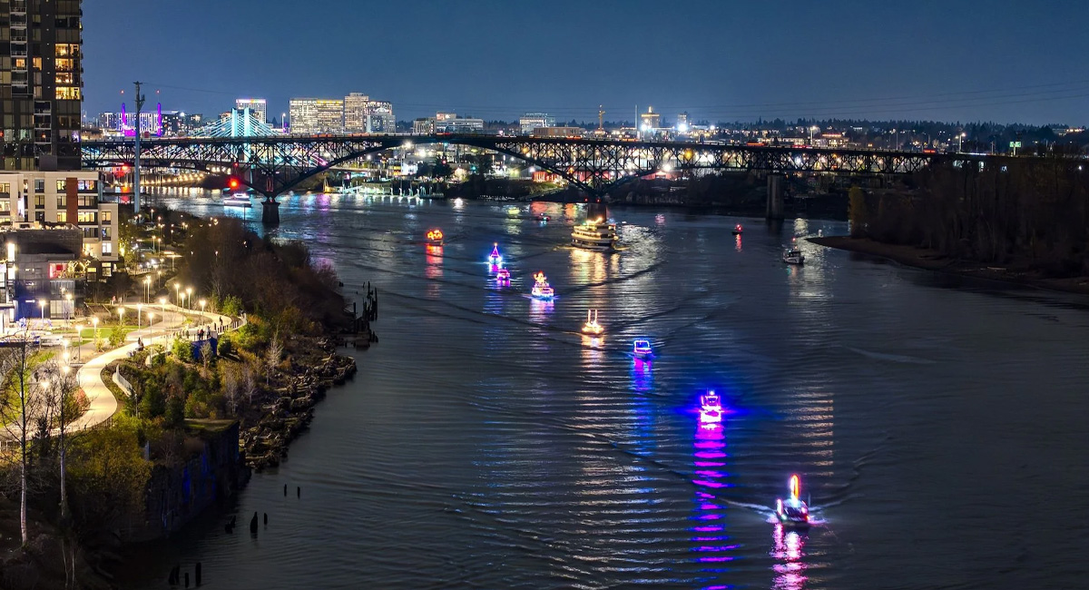 Boats with bright holiday lights on the Willamette River through Portland.