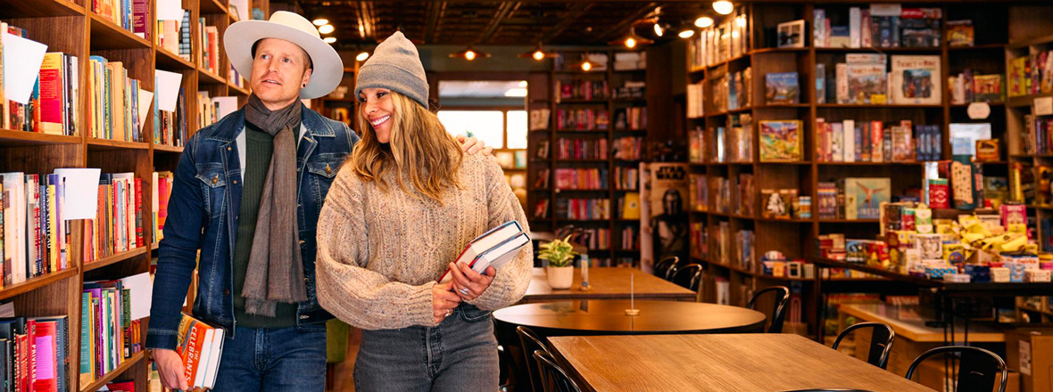 A man and woman walking around in a bookstore.