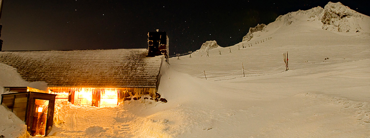 A mountain-side cabin glows at night.