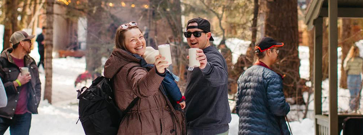 Two people cheering with a drink in hand towards the camera.
