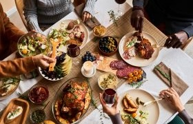 Overhead view of a diverse group sharing a festive meal at a decorated table.