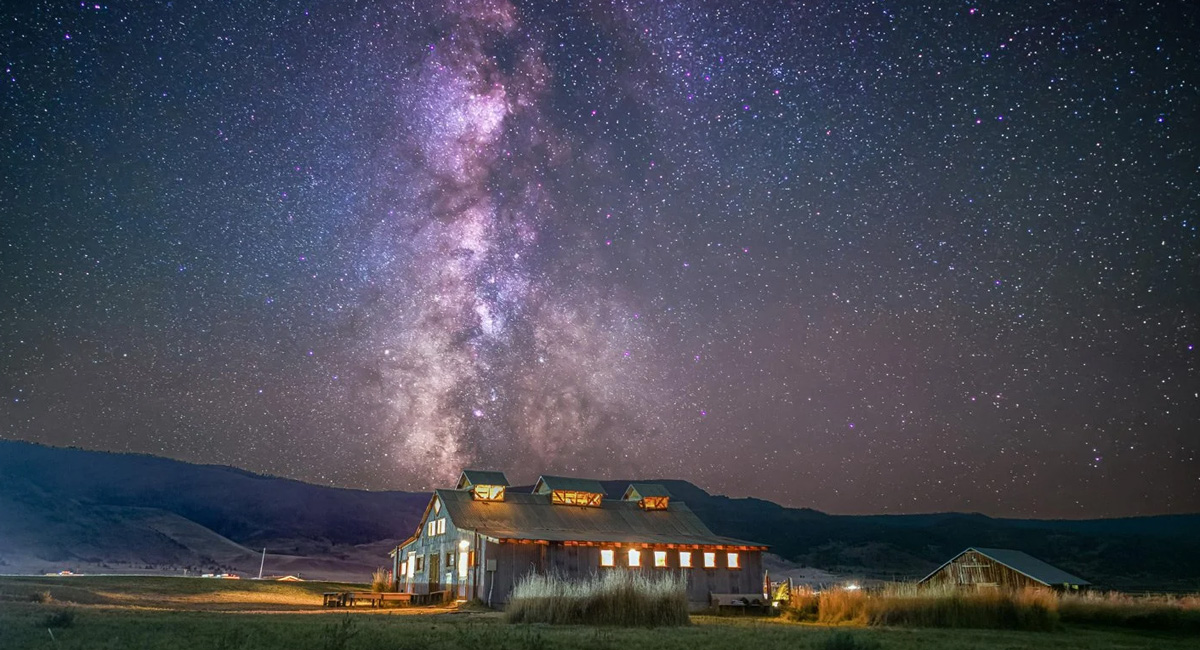 A rustic lodge set against the backdrop of the milky way and thousands of stars.