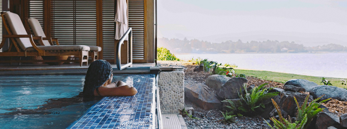 A woman at the edge of a ground-floor pool overlooking the view of the coast.