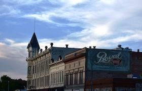 Historic downtown buildings with a vintage “Royal” painted sign and cloudy blue sky above.