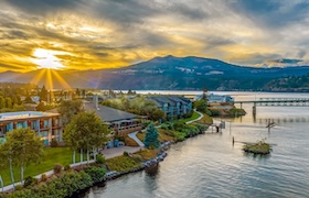 Sunset over Hood River waterfront with hotel buildings, marina docks and mountains along the Columbia River.