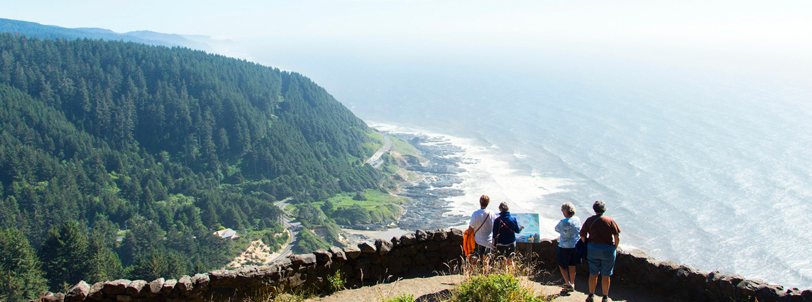 People stand at a high-elevation overlook with the ocean and Hwy. 101 below
