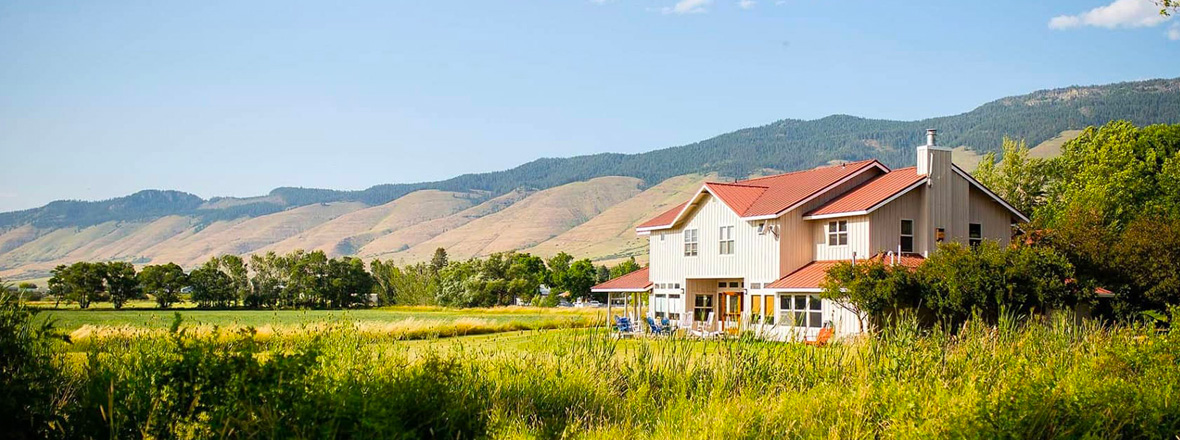 A two story building in a natural setting with dry hills in the background.