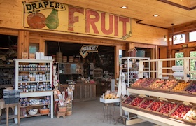 Farm market interior with fresh fruit displays and shelves of goods.