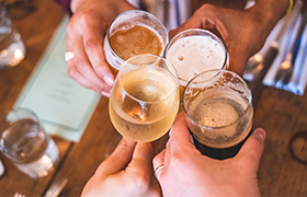 People clinking glasses of wine and beer in a celebratory toast.