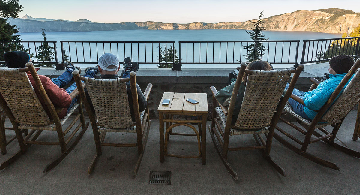 People sitting in rocking chairs overlooking a lake.