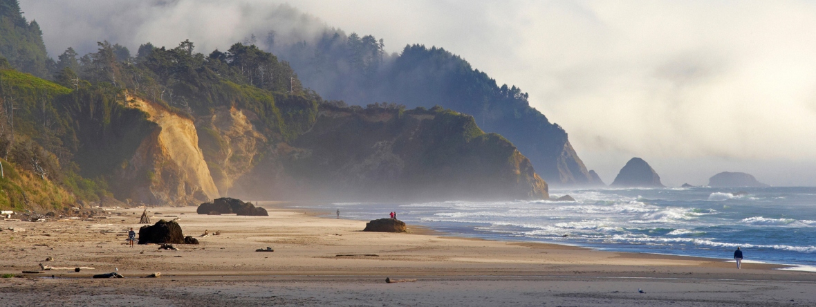 Ocean, bluffs, sand and clouds in sky.