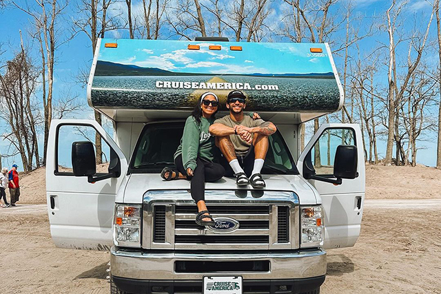 Man and woman sitting on hood of van