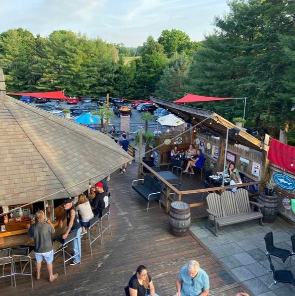 Groups of people sitting at a tiki bar and on an outdoor patio at dusk