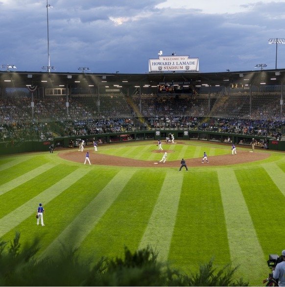 Kids playing baseball on a baseball field at dusk