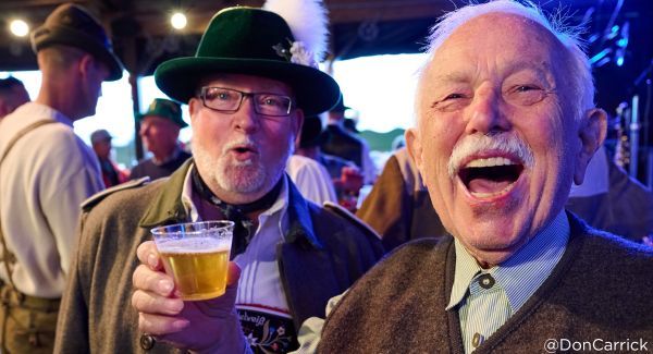 Faces of two men, one smiling and one shocked, as they drink beer