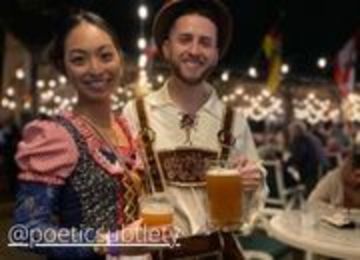 Woman in a dirndl dress and a man in lederhosen holding beers