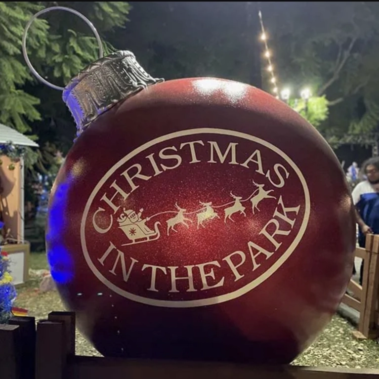 A large holiday ornament with the logo for Christmas in the Park displayed on it.
