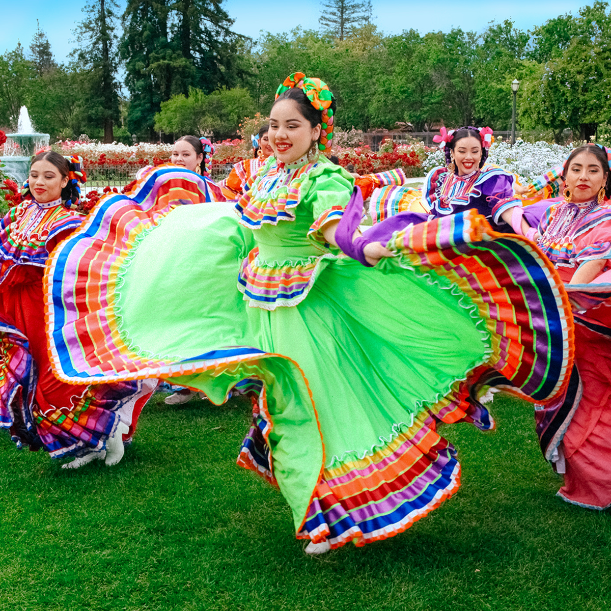 Dancers in traditional Mexican clothing performing a dance in the daytime.
