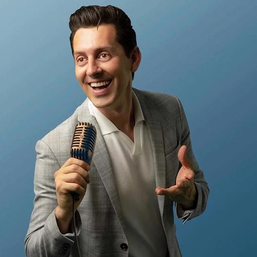 Comedian Max Amini holding a microphone against a teal background.