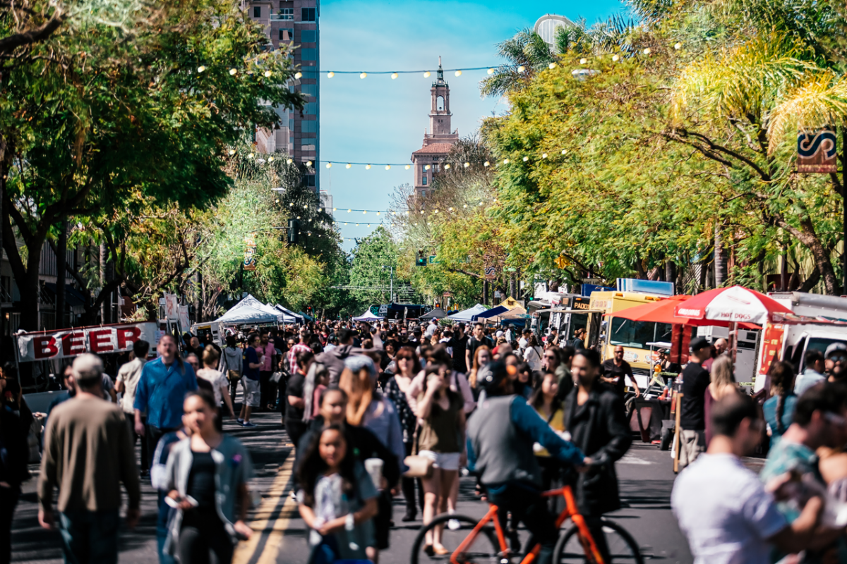 A crowd walking down a street full of street vendors.