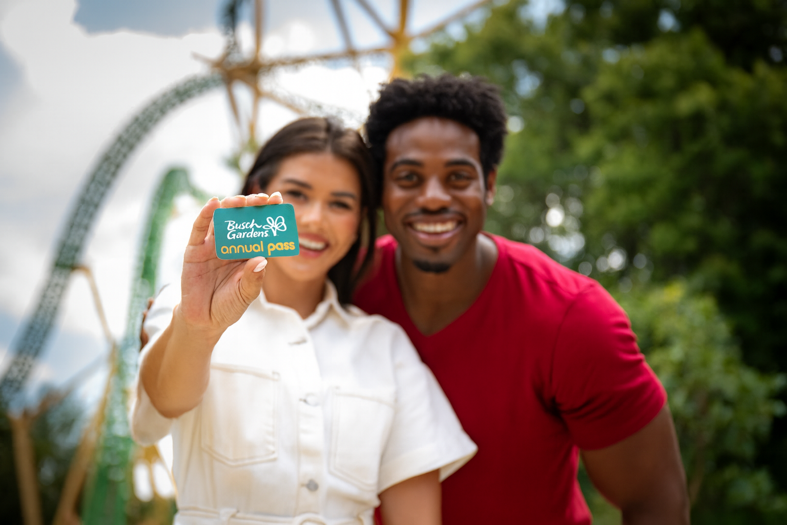 A young couple holding an illustration card of an Annual Pass to Busch Gardens. 