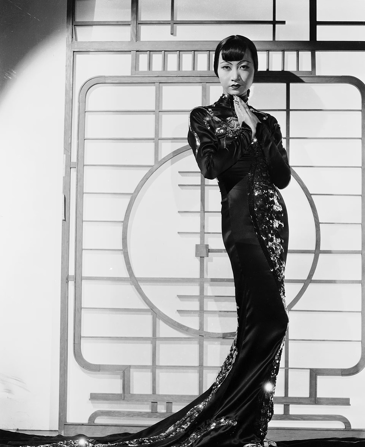 Black and white photo of a woman posing while wearing a tradition Asian style dress.