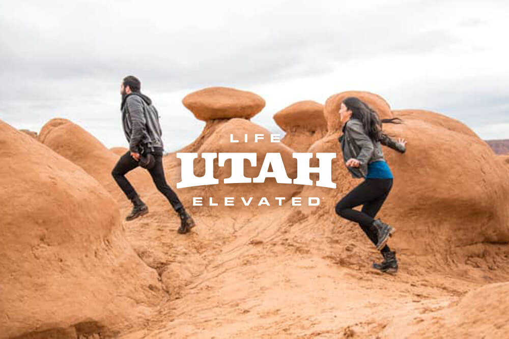 two people trekking through goblin valley in utah