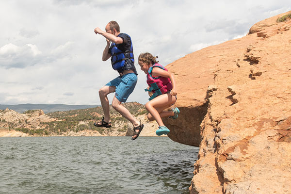 a man and a child jumping off a rock into water
