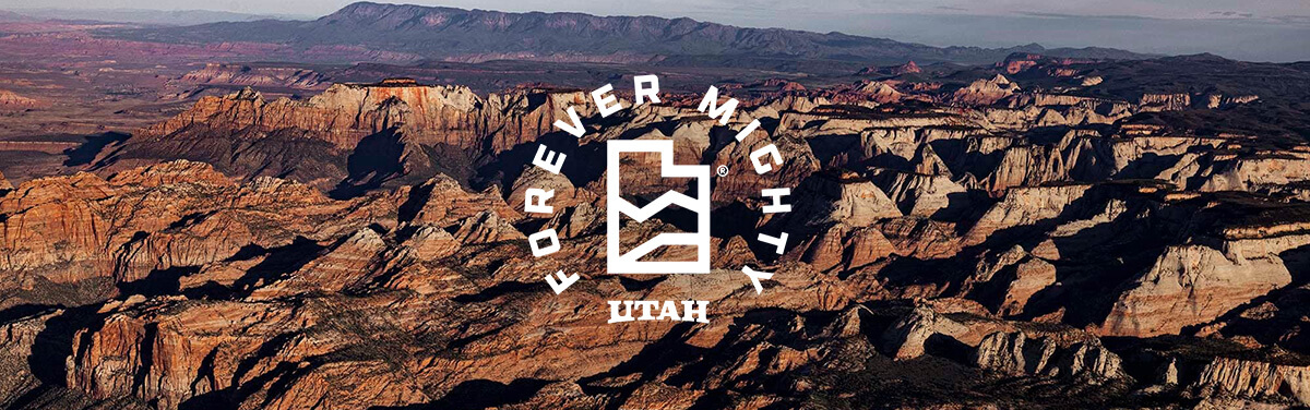 a bird's eye view of a utah canyon with a white overlay reading "forever mighty"
