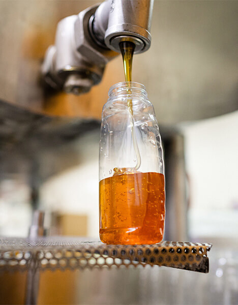 honey pouring out of a spigot into a jar
