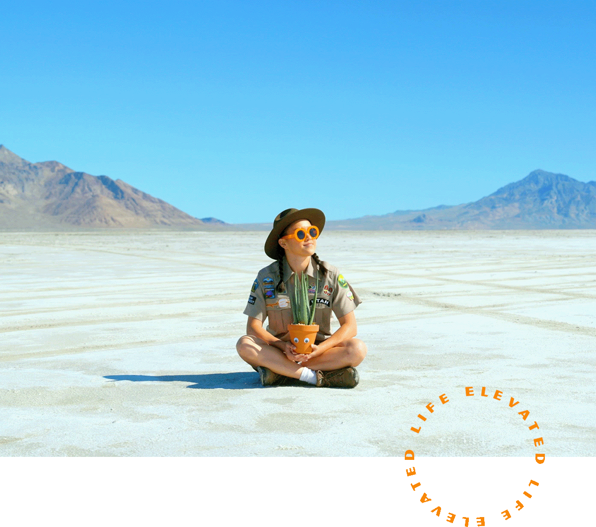 a woman sitting in the middle of the desert with potted plant