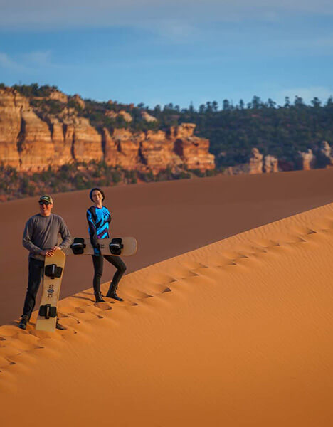 two people standing in the desert with their snowboards