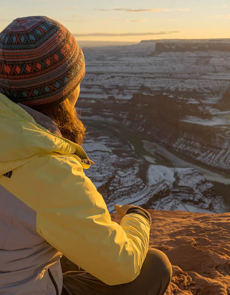 a woman overlooking a canyon covered with a dusting of snow