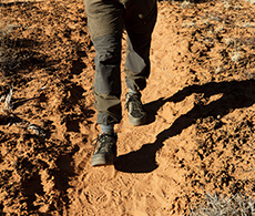 a close up of someone's feet as they walk through desert sand