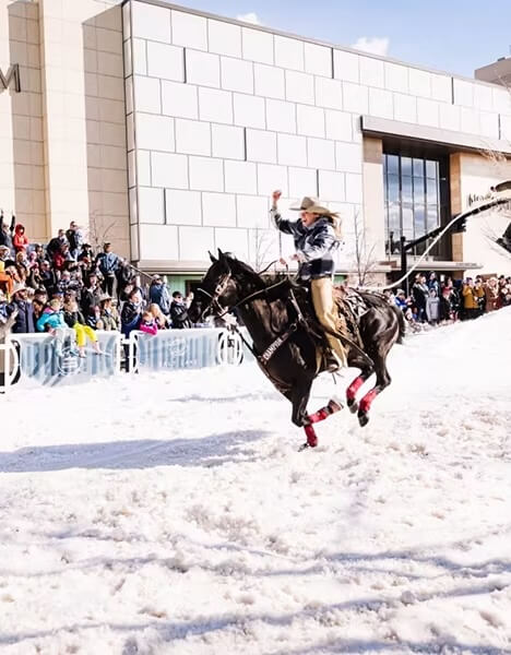 a cowboy riding a horse through snow in front of a crowd