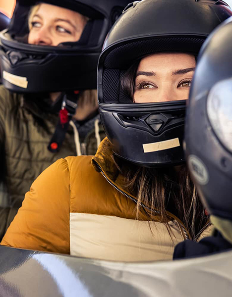 two women wearing helmets sitting in a bobsled