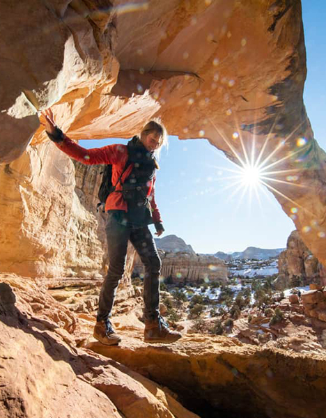 a person standing on a rock underneath an arch in a desert