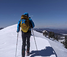 a skier with a backpack hiking up a snow covered slope