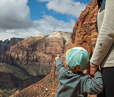 a person holding a baby in front of a canyon