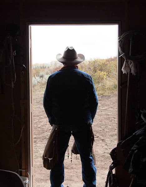 a man in a cowboy hat standing in front of a door