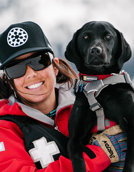 a woman is holding a black dog in her arms
