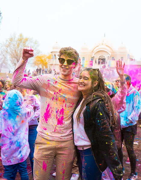 A man and a woman splattered with various colored paint.